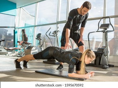 Man and woman doing electro muscular stimulation training in a modern gym