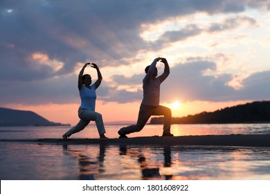 Man And Woman Doing Tai Chi Chuan At Sunset On The Beach.  Solo Outdoor Activities. Social Distancing. Healthy Lifestyle  Concept. 