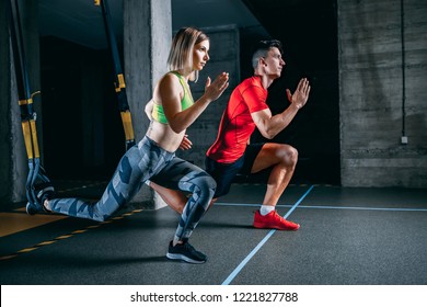 Man And Woman Doing TRX Workout At The Gym.