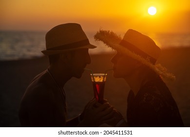 A man and a woman are drinking a cocktail at sunset by the sea. Selective focus. Nature.