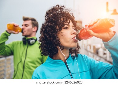 Man And Woman Drinking Energy Drink From Bottle After Fitness Sport Exercise