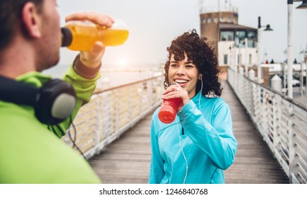 Man And Woman Drinking Energy Drink From Bottle After Fitness Sport Exercise