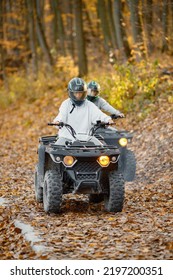 Man And Woman Driving Quad Bike In Autumn Forest