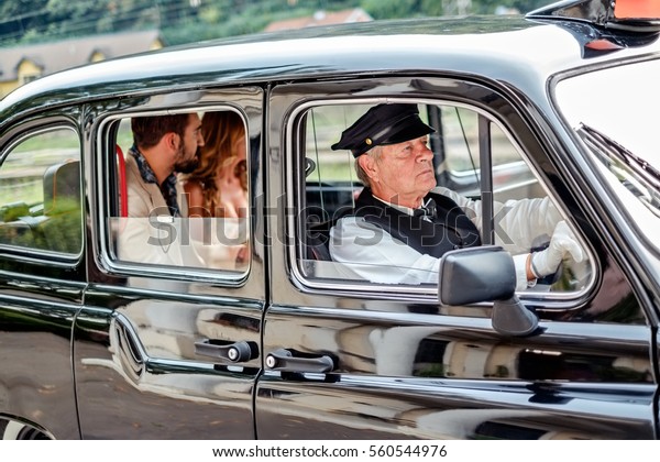 Man and woman driving in vintage taxi and looking\
through the window