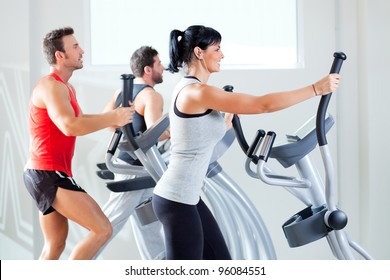 man and woman with elliptical cross trainer in sport fitness gym club - Powered by Shutterstock