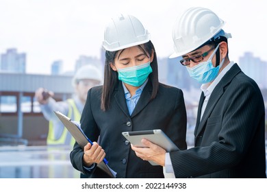 Man And Woman Engineers And Workers Using Tablet Device And Meeting At Rooftop Of Solar Cell Panel In Background. Asian, People Operate On Site Renewable Energy Construction.