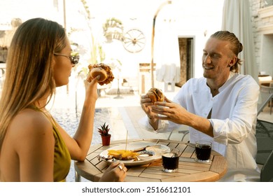 A man and woman are enjoying delicious hamburgers by the poolside, savoring their meal while conversing - Powered by Shutterstock