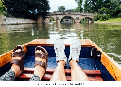 Man and woman feet on a boat punting in the river in  Cambridge. Focus on feet.