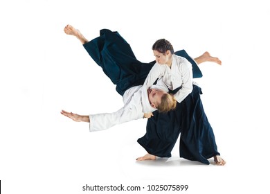 Man and woman fighting at Aikido training in martial arts school. Healthy lifestyle and sports concept. Man with beard in white kimono on white background. Karate woman with a concentrated face.