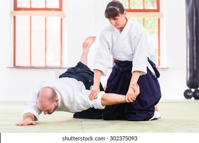 Man and woman fighting at Aikido training in martial arts school 