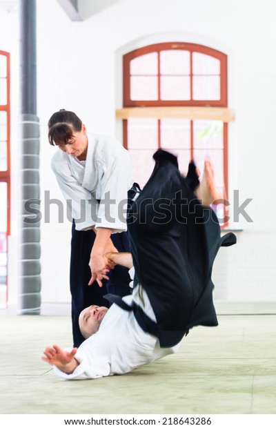 Man and woman fighting at Aikido training in martial\
arts school 