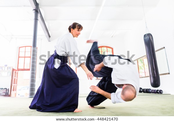 Man and woman fighting at Aikido training in martial\
arts school 