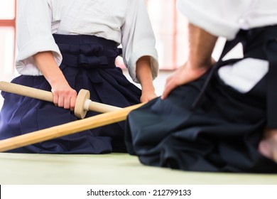 Man and woman fighting with wooden swords at Aikido training in martial arts school 