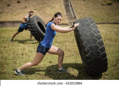 Man And Woman Flipping A Tire During Obstacle Course In Boot Camp