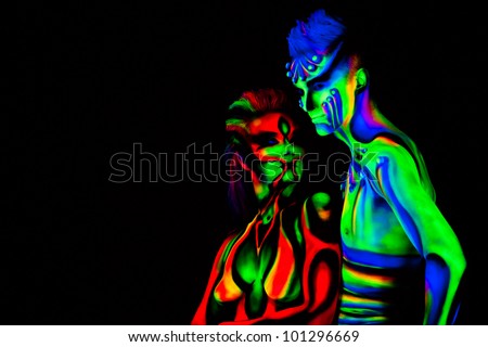 Man and woman with fluorescent bodyart. Black background. Studio shot