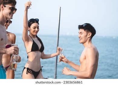 Man and woman friends group enjoy celebration party and fun luxury summer outdoor lifestyle by drinking champagne together, travel vacation on catamaran yacht boat sailing in tropical sea sunset on