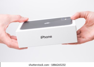 Man and woman hand holding a box with black iPhone 11 on the grey background, December 2020, San Francisco, USA