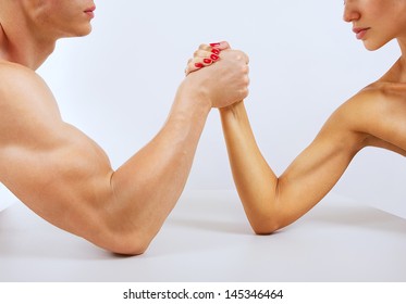 A man and woman with hands clasped arm wrestling