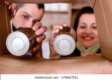 Man And Woman Hands Loading Canned Food In Donation Box.Help For  Economy Poor People And Charitable Foundation Concept.Close Up On Hands Packing Food 