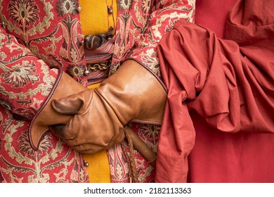 Man And Woman Hands An Ornate Vintage Robe With Retro Weapons Behind An Old Belt. Male And Female Hands In Antique Clothes With A Cane