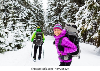 Man and woman happy couple hikers trekking in white winter woods and mountains. Young people walking on snowy trail with backpacks, healthy lifestyle adventure, camping on hiking trip, Poland.