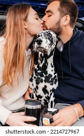 Man With Woman Have Fun With Their Dog Outdoors In Forest Near Modern Black Car.