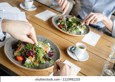 Man And Woman Having Business Lunch At Restaurant Sitting At Table Eating Two Plates Of Fresh Vegetable Salad Close-up