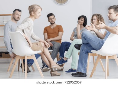 Man and woman having coaching session about assertiveness in group of people