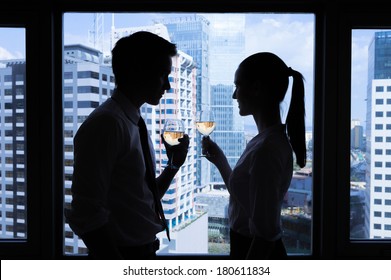 Man and woman having glass of wine in the office. Business celebration. - Powered by Shutterstock