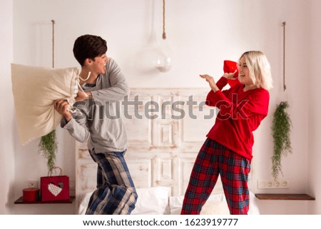 Man and woman having a pillow fight in the bedroom 