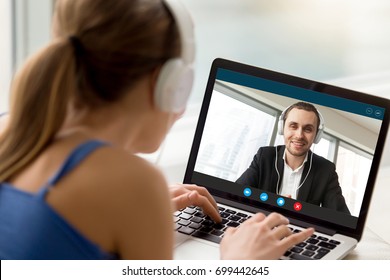 Man and woman in headphones communicating online by video call, looking at full screen videoconferencing app window, webcam videochat, virtual dating, long distance relationships, close up rear view - Powered by Shutterstock