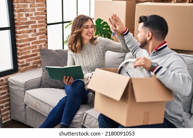 Man And Woman High Five Sitting On Sofa With Dog At New Home