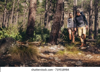 Man And Woman Hikers Trekking A Rocky Path In Forest. Hiker Couple Exploring Nature Walking Through The Woods.