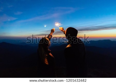 The man and a woman hold firework sticks. evening night time