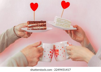 a man and a woman hold in their hands plates with a cake decorated with a red heart-shaped lollipop and mugs with hearts. Couple in love celebrating Valentine's Day