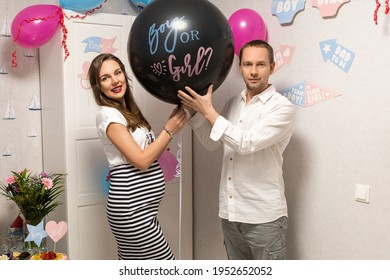 Man and woman holding black balloon with "boy or girl?" on gender reveal party. Celebration. Pregnancy. Family.

 - Shutterstock ID 1952652052