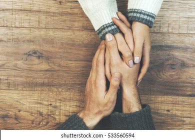 man and a woman holding hands at a wooden table - Shutterstock ID 533560594