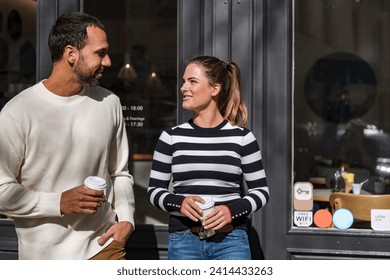 Man and woman holding takeaway cups outside a cafe talking - Powered by Shutterstock