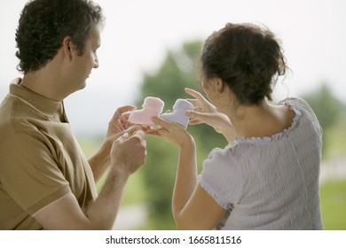 Man And Woman Holding Up Two Baby Boots