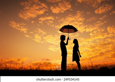 Man And Woman Holding Umbrella In Evening Sunset Silhouette