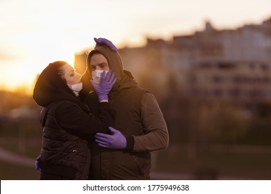 A man and a woman in hoods, in protective masks and purple gloves posing in the setting sun in the city. - Shutterstock ID 1775949638