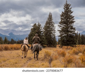 A man and woman horseback riders make their way along a trail in the Ya Ha Tinda Ranch in Alberta, Canada during autumn - Powered by Shutterstock