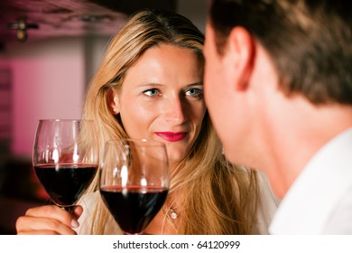 Man And Woman In A Hotel Bar In The Evening Having Glasses Of Red Wine And A Little Flirt