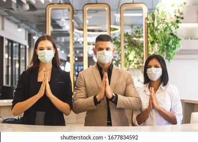 Man And Woman Hotel Receptionist Wearing Medical Mask Greeting Thailand Style.