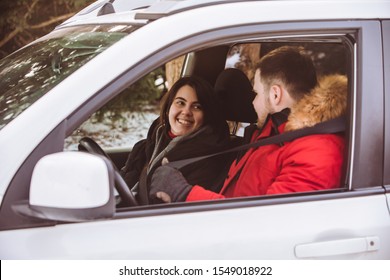 Man And Woman Inside Car In Winter Clothes.