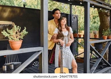 A man and a woman, an interracial couple, stand next to a guitar in a natural setting, enjoying a romantic moment together. - Powered by Shutterstock