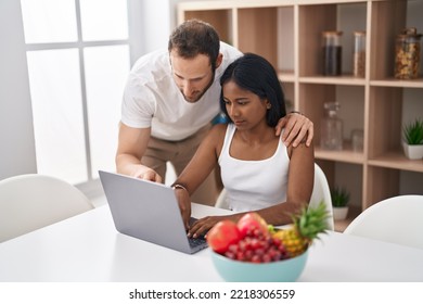 Man And Woman Interracial Couple Using Laptop Sitting On Table At Home