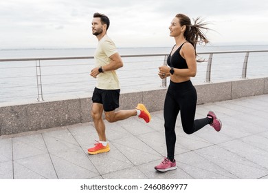 A man and a woman jog side by side along a waterfront promenade, enjoying a healthy, active lifestyle together.

 - Powered by Shutterstock