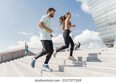 A man and a woman jog up stairs in an urban area under a bright sky, focused on their workout.

 - Powered by Shutterstock