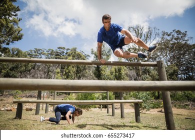 Man And Woman Jumping Over The Hurdles During Obstacle Course In Boot Camp